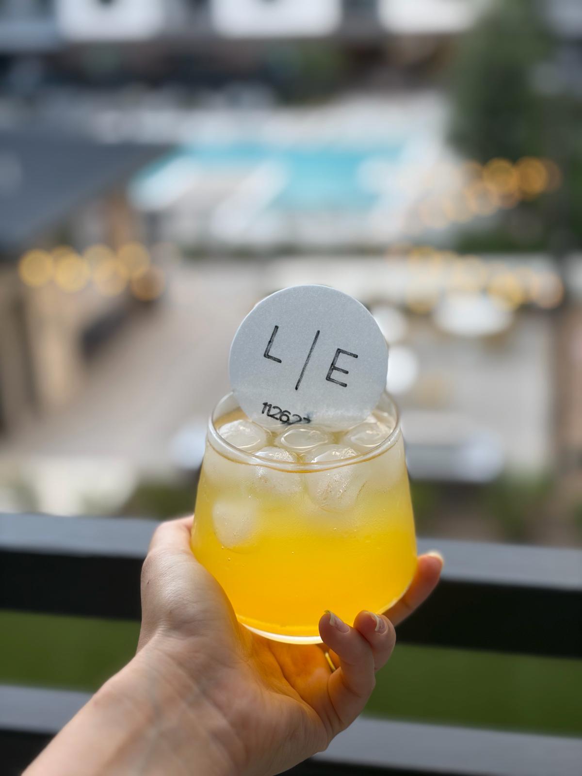 Hand holding a stemless glass with L|E monogram circular topper