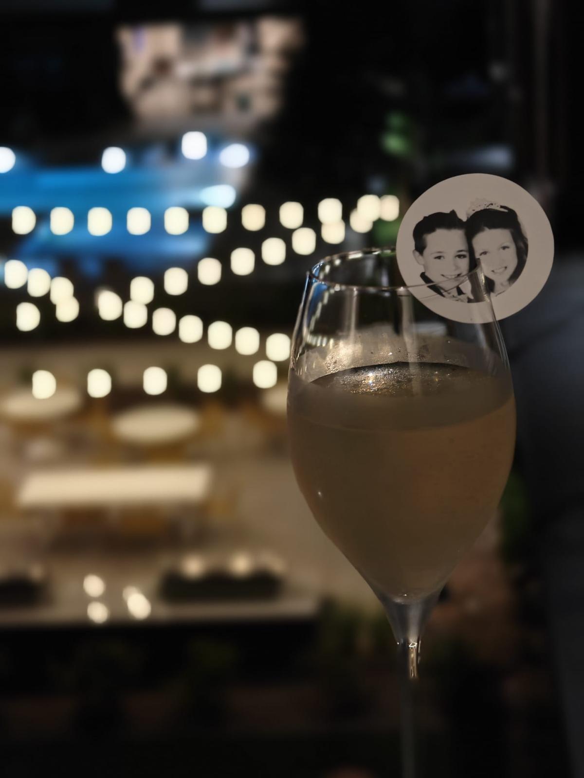 Champagne flute with couple photo topper against string lights